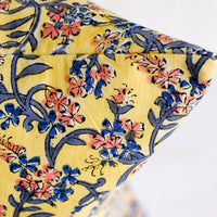 5: A block printed throw pillow in yellow with blue and pink floral print.