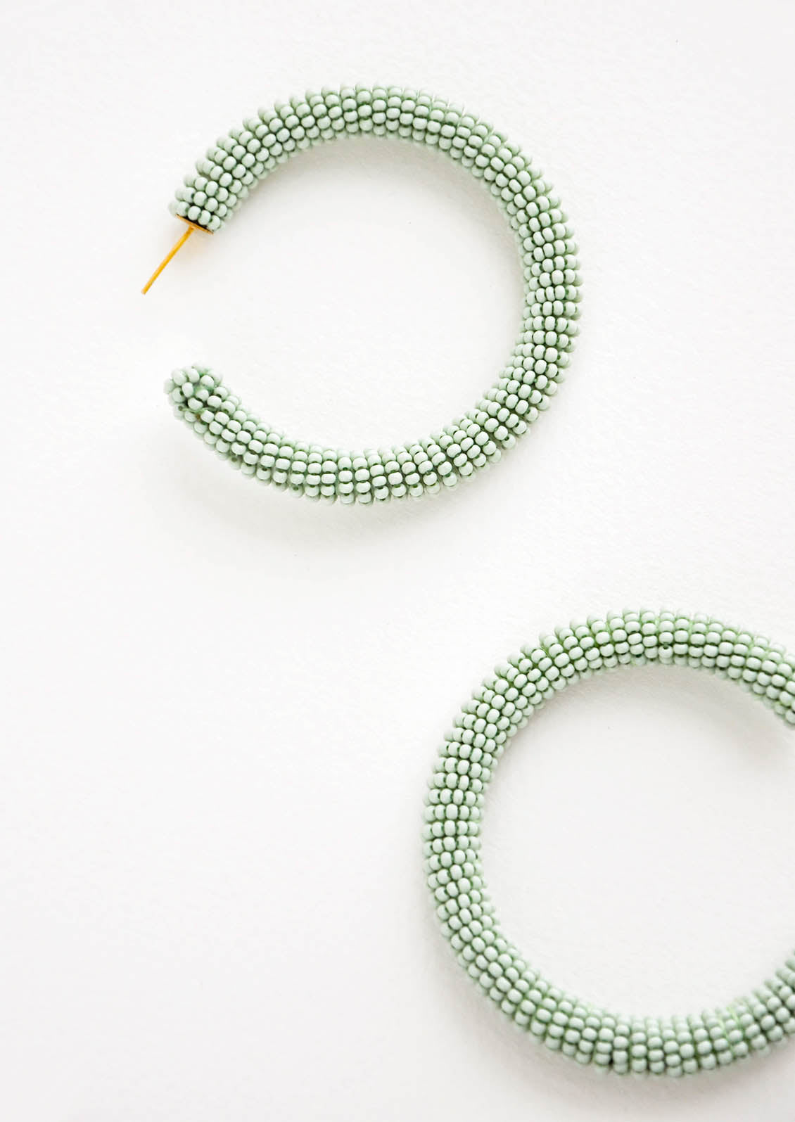 Thick hoop earrings of mint green colored glass beads.