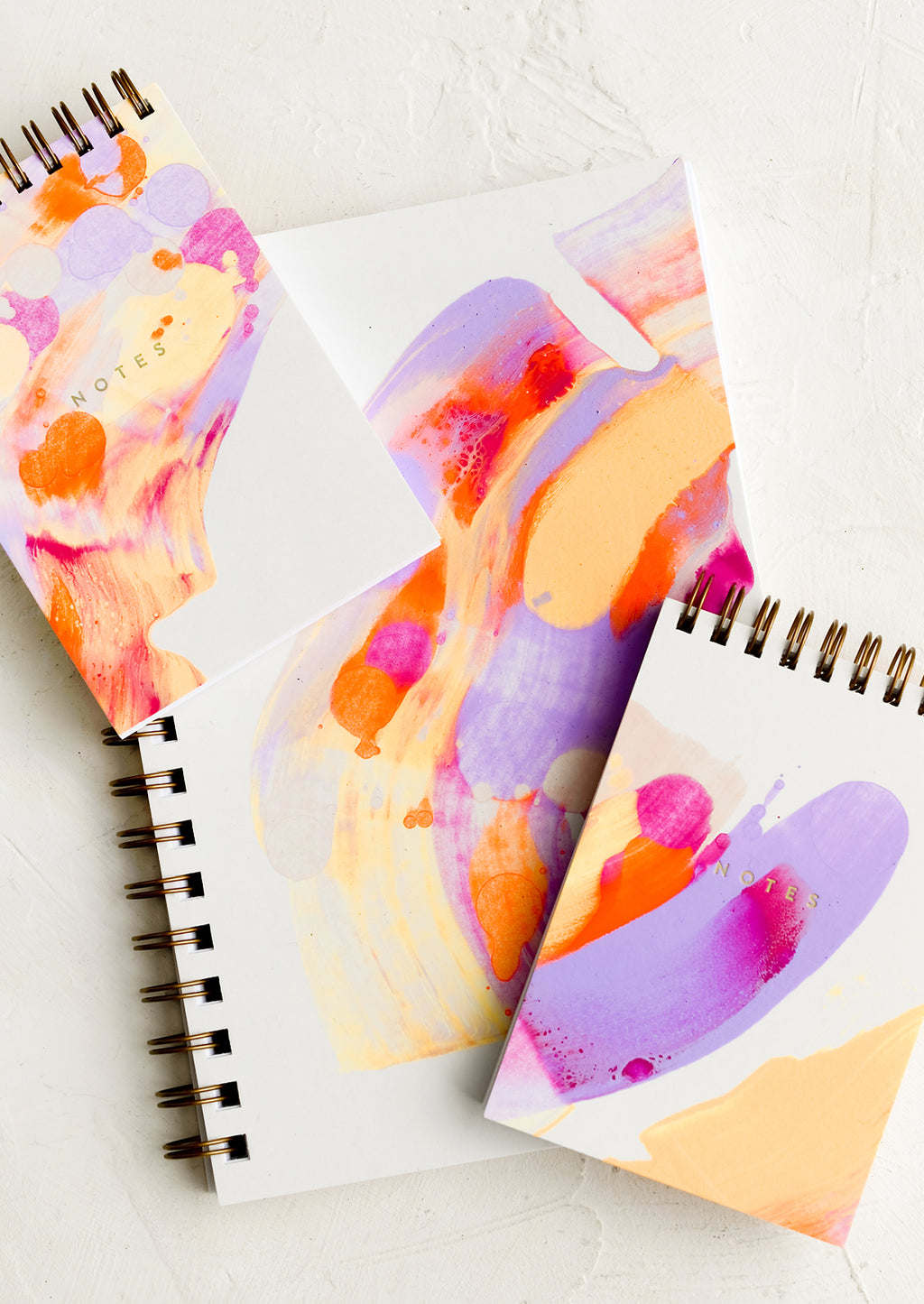 1: Vibrantly painted white notebooks with purple, pink and orange paint.
