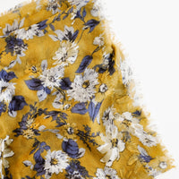 Green Ochre: Close up shot of scarf with dark yellow background and multi-colored blue and white floral pattern 