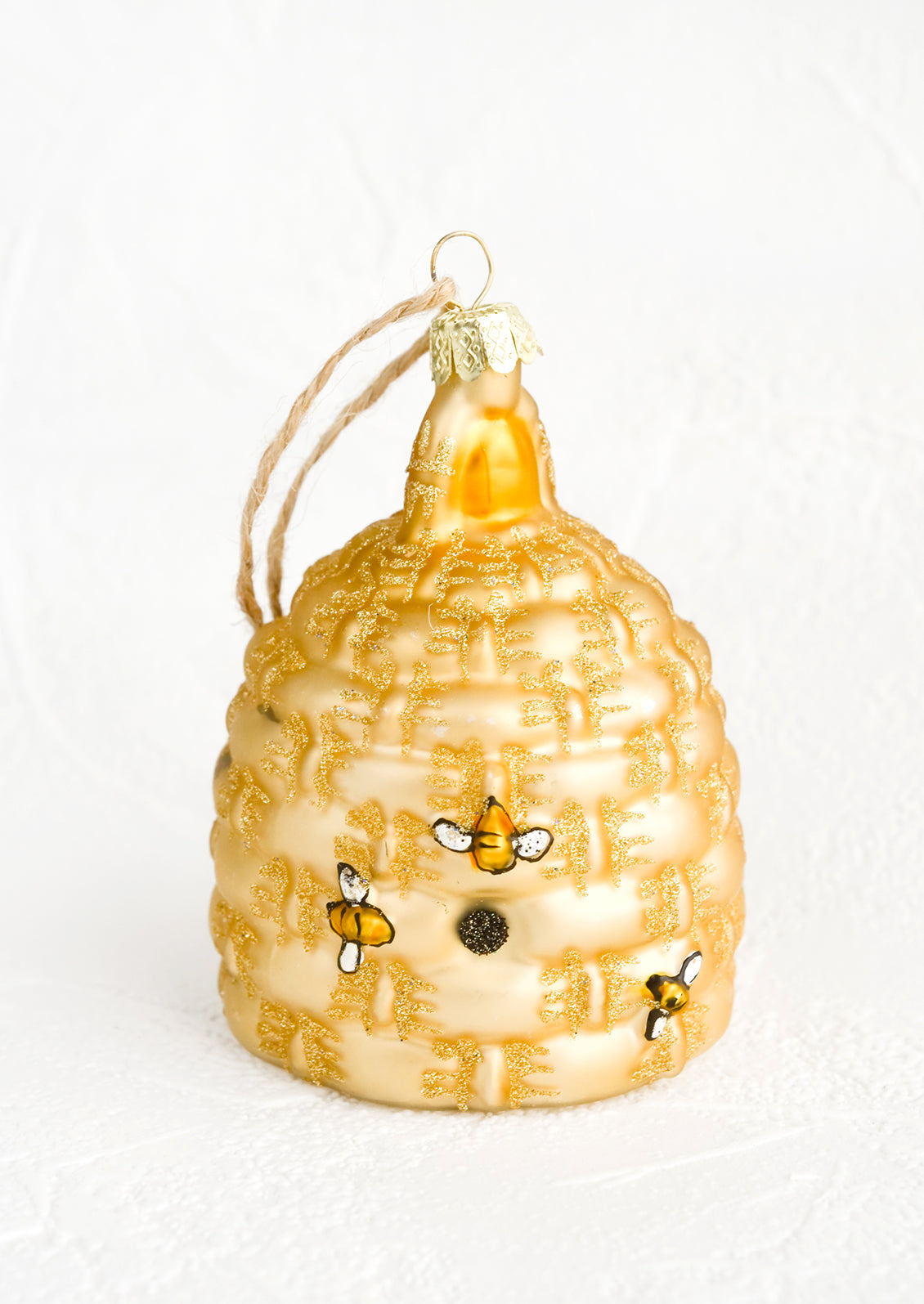 A glass ornament in the shape of a beehive with painted on bees.