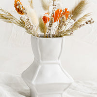 Short: A short geometric vase in white ceramic, shown with dried flowers.