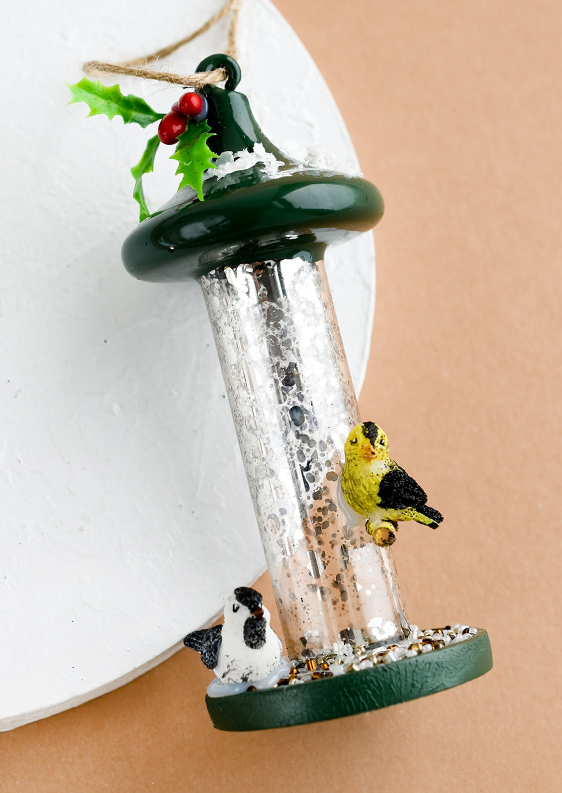 A holiday ornament of a bird feeder with goldfinch and chickadee.