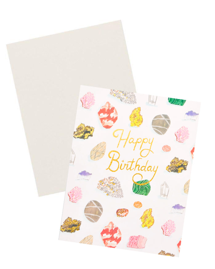 Notecard with colorful drawings of gems and minerals and the text "Happy Birthday" in gold foil, with white envelope.