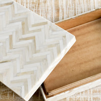 2: A rectangular storage box in cream colored herringbone pattern.