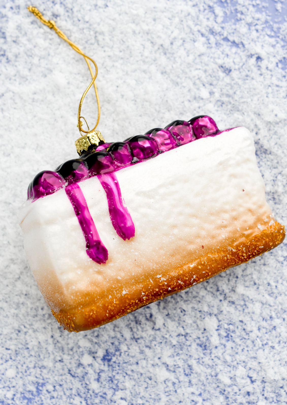 A glass holiday ornament of blueberry cheesecake slice.