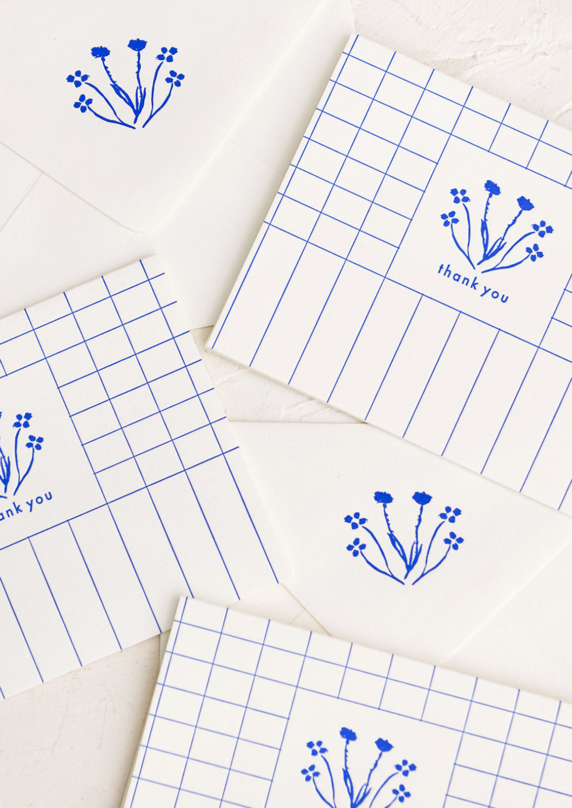 A set of blue and white grid patterned thank you cards with drawn floral imagery.