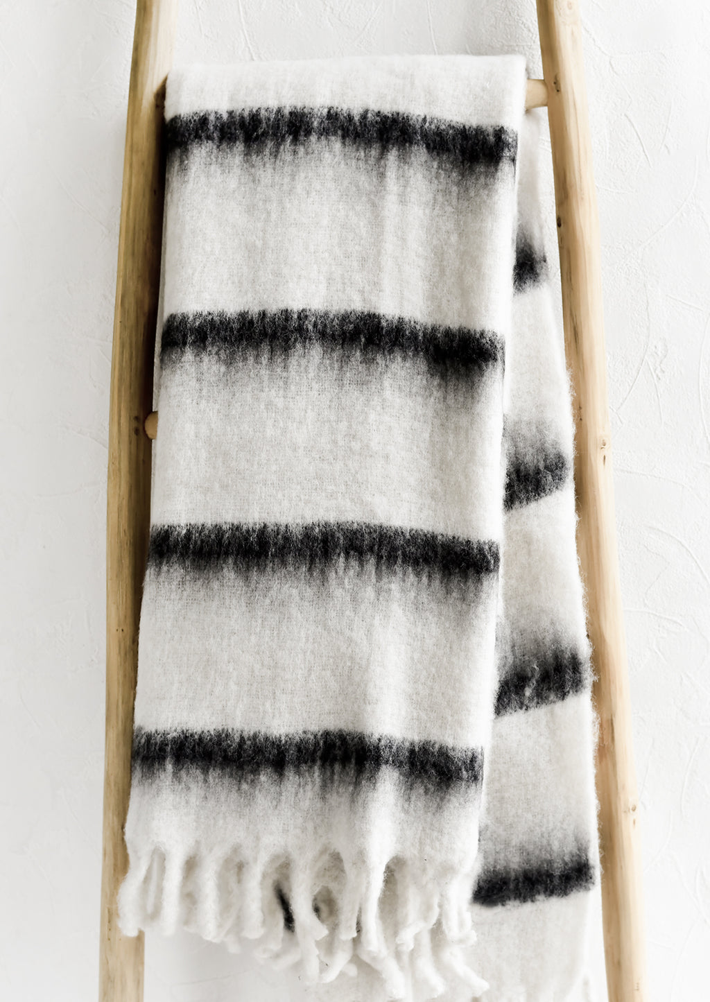 1: A fuzzy throw blanket in white with black stripes.