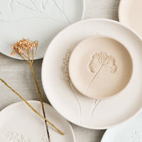 Small / Sand: Stacked pastel porcelain plates with plant imprint designs.