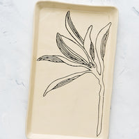 Magnolia: A rectangular ceramic tray in natural bisque color with an etched black drawing of a Magnolia branch.