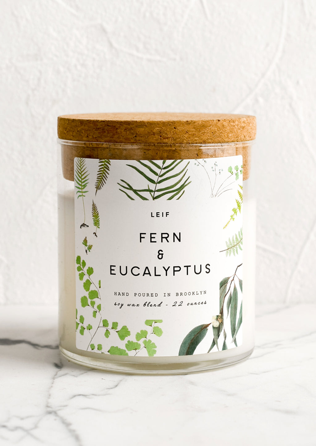 Fern & Eucalyptus: A glass candle with a cork lid and white botanical printed label reading "fern and eucalyptus".