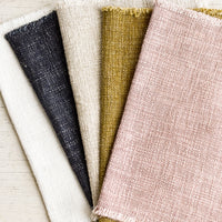 1: A stack of slub boucle textured placemats in assorted colors.