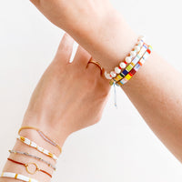 2: A woman's hands crossed with her wrists featuring many different bracelets.