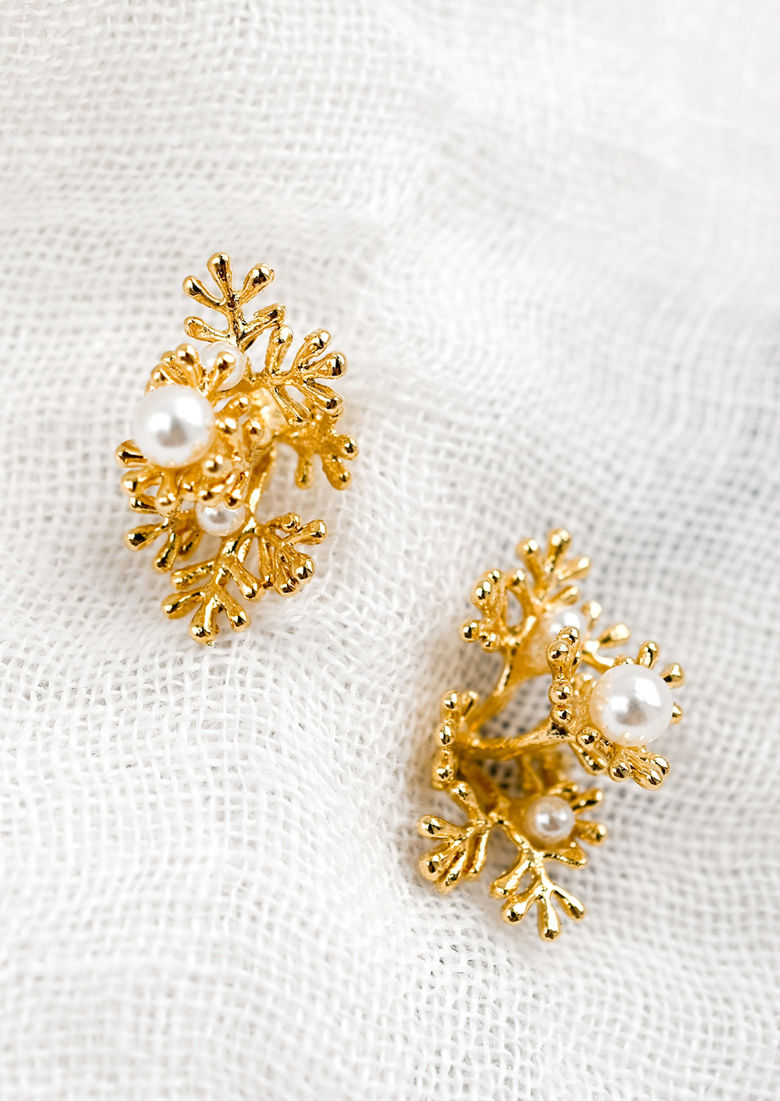 A pair of coral shaped gold earrings with small and large pearl detailing.