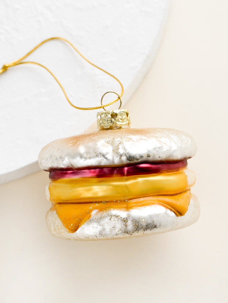 1: A decorative glass ornament in the shape of an egg breakfast sandwich on english muffin.