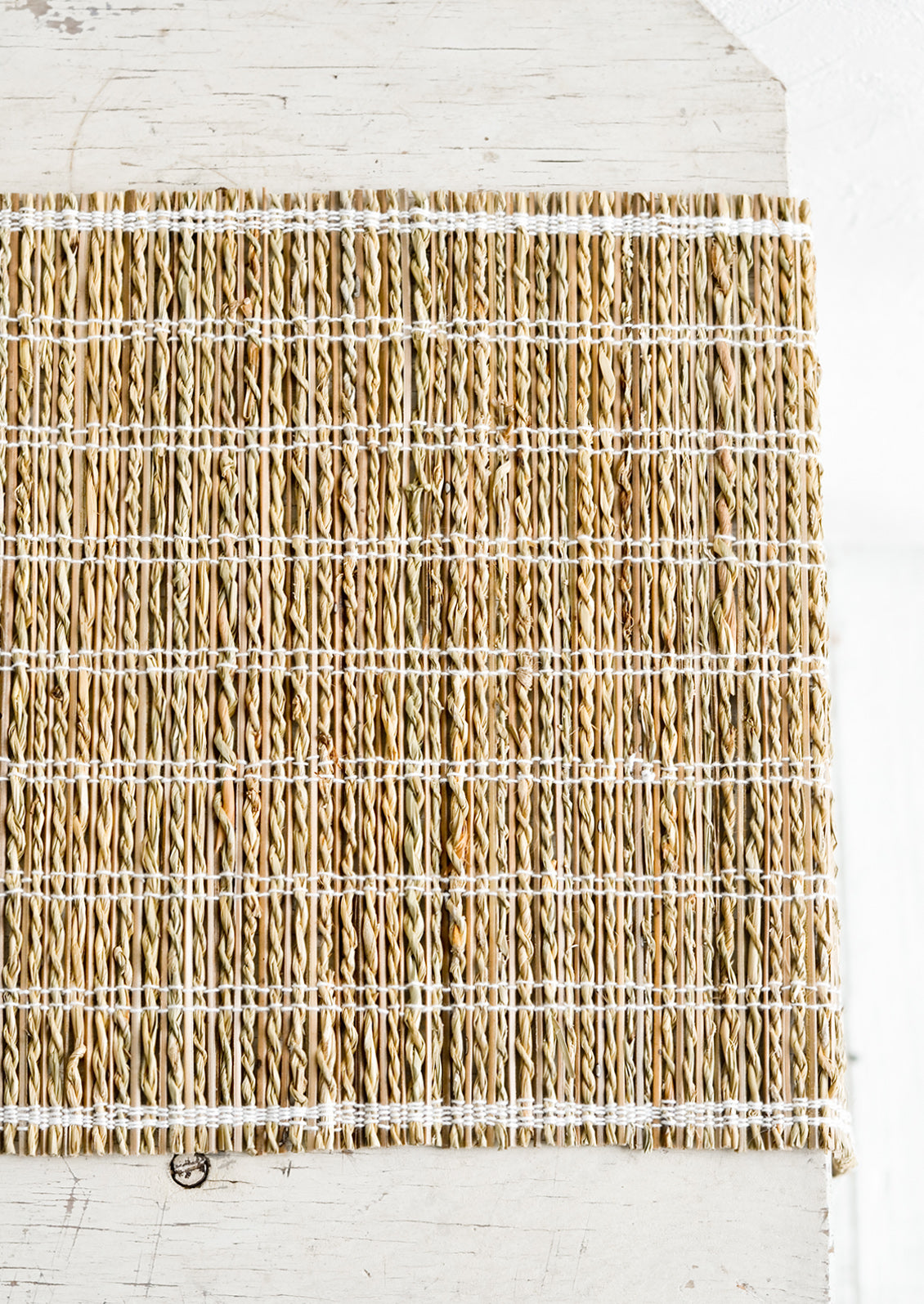 A table runner made of natural banana fiber with white stitching.