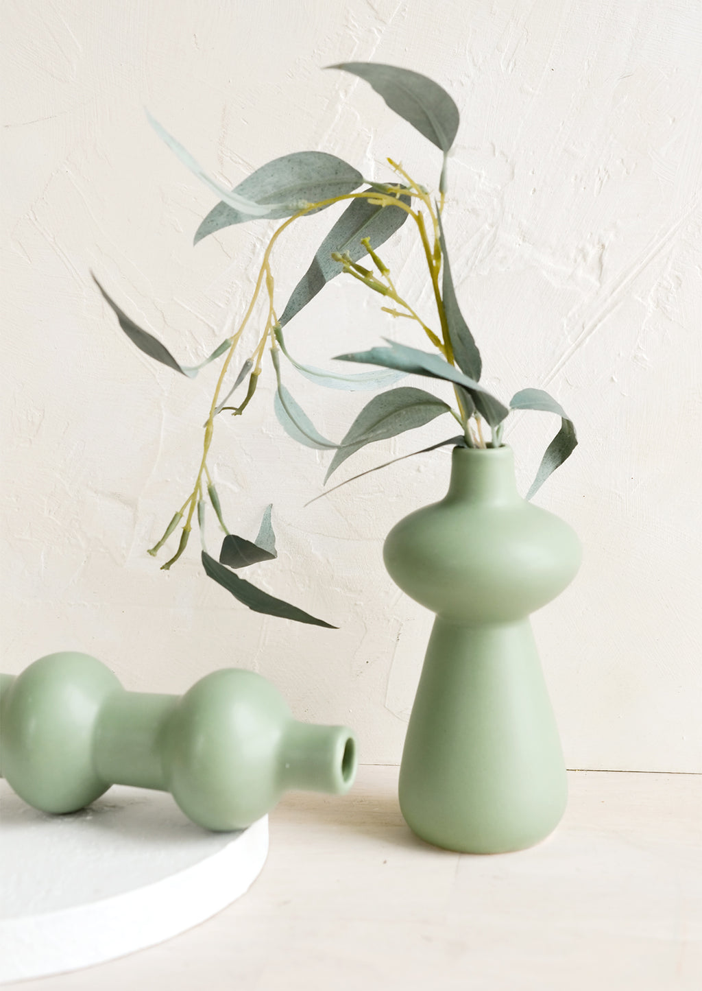 1: Mint green ceramic bud vases in curvy silhouettes.