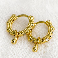 1: A pair of textured gold hoop earrings with crystal detailing.