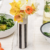 2: A black and white vase on a table with daffodils.