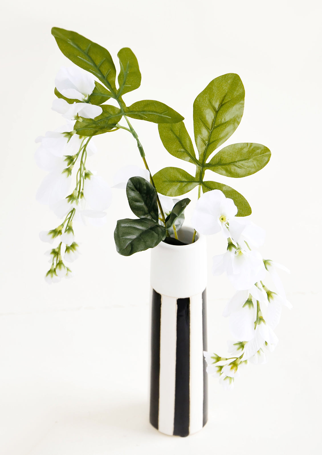 Tall and skinny black and white striped ceramic vase with flowers