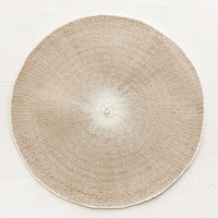 Taupe: A round straw placemat in taupe with white spot at center.