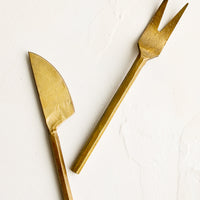 Fork: A canape sized fork and knife with primitive inspired shapes in brass.