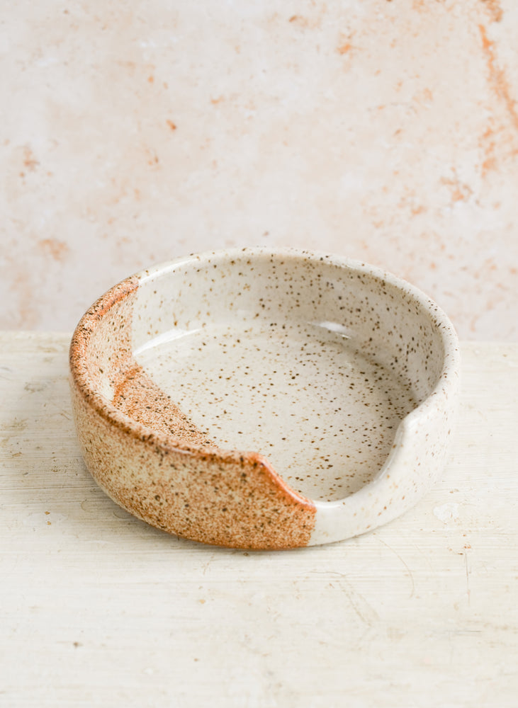 1: A ceramic spoon rest in speckled white and rust glaze.