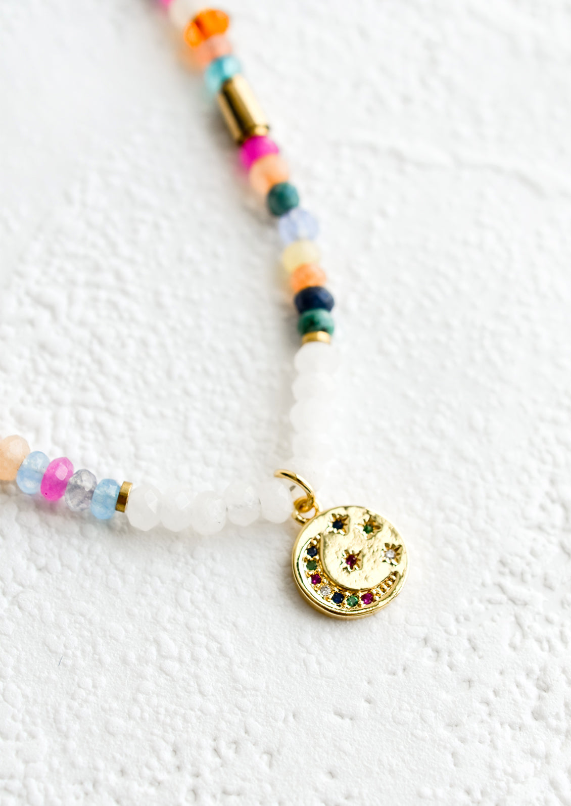 A gold charm with moon and stars in multicolor crystals.