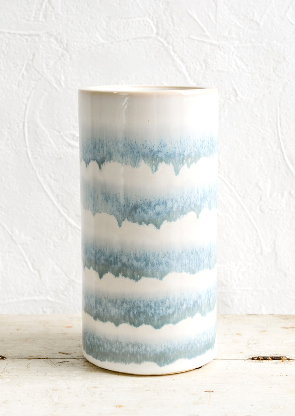 2: A tall cylindrical ceramic vase with blue and white stripes.
