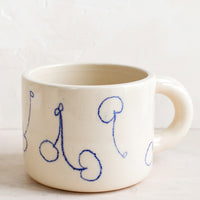 1: An ivory ceramic mug with line drawing cherries in blue.