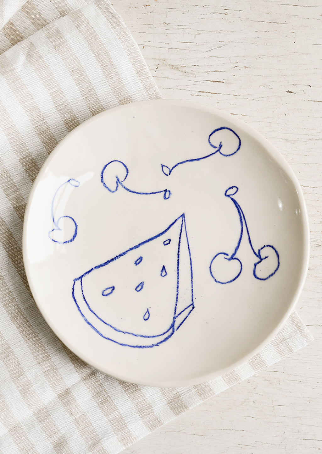 1: A ceramic side plate with still life fruit drawings in blue.