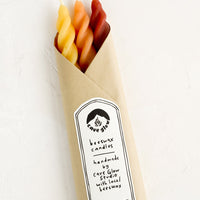 Sunrise Multi: Three spiral beeswax tapers in orange, red and yellow wrapped in kraft paper.