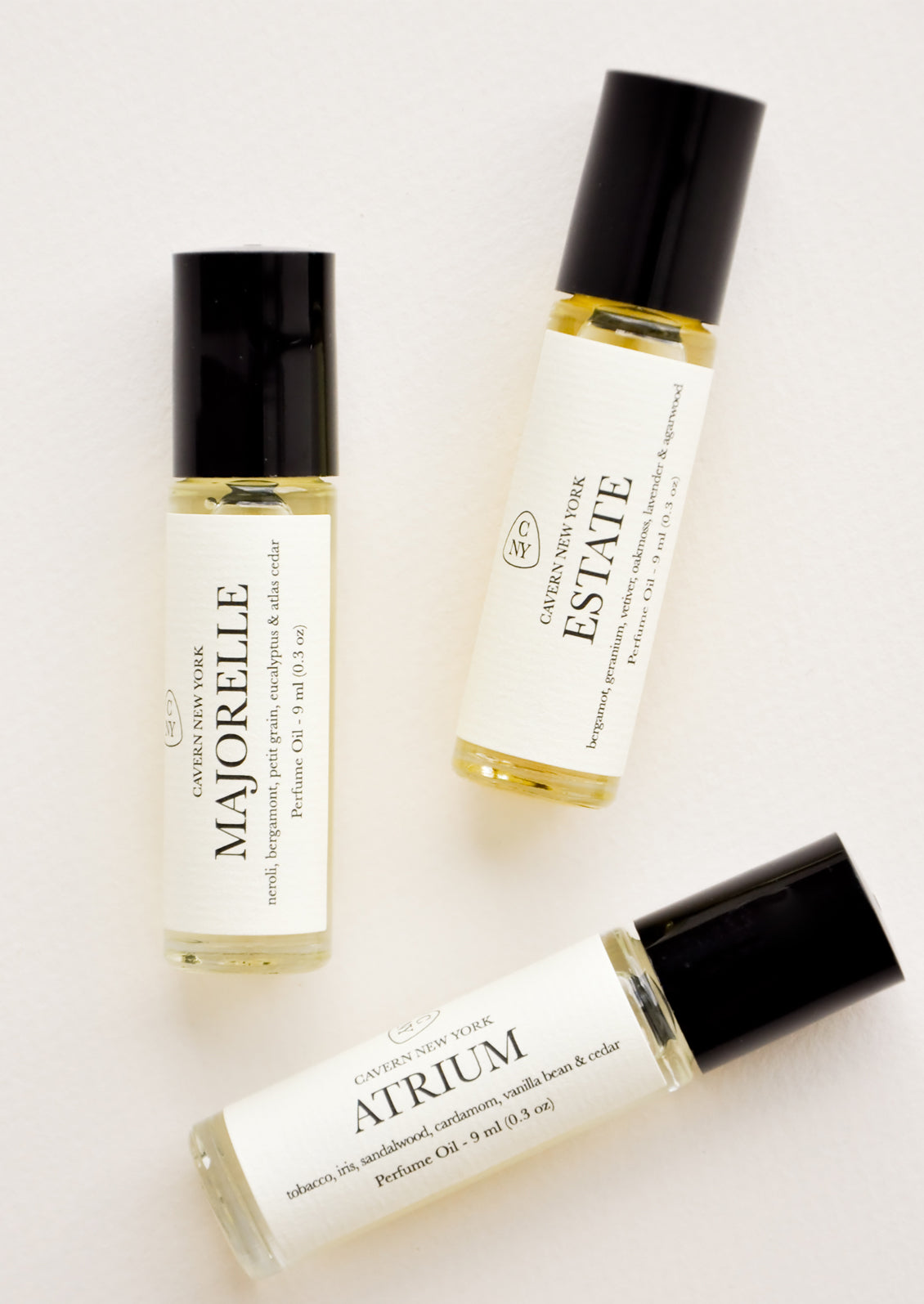 three glass rollerball bottles with black caps, white labels with black text