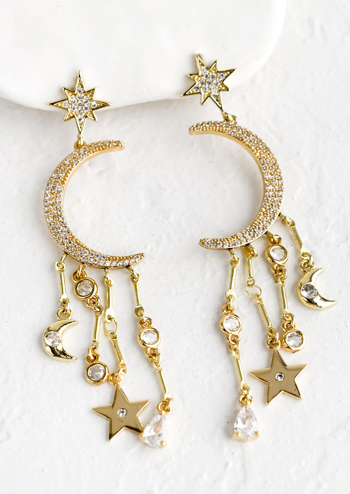 A pair of gold earrings with crystal moon and star and dangling stars and moons.