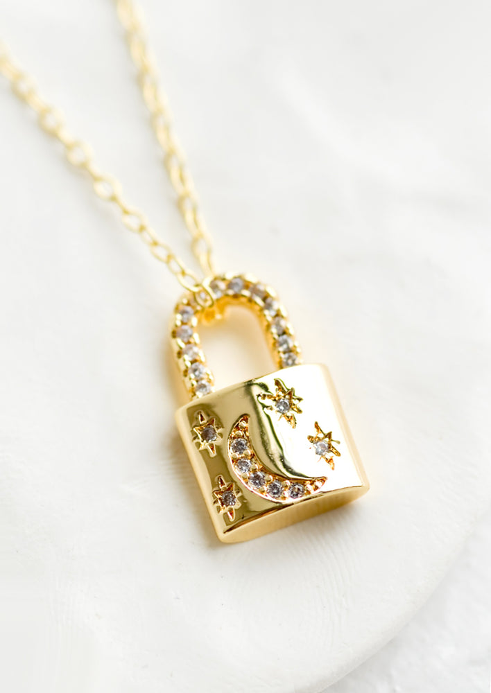 A gold padlock pendant encrusted with moon and stars.