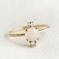 1: A gold ring with large center opal stone and two small white topaz stones.