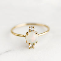 2: A gold ring with large center opal stone and two small white topaz stones.