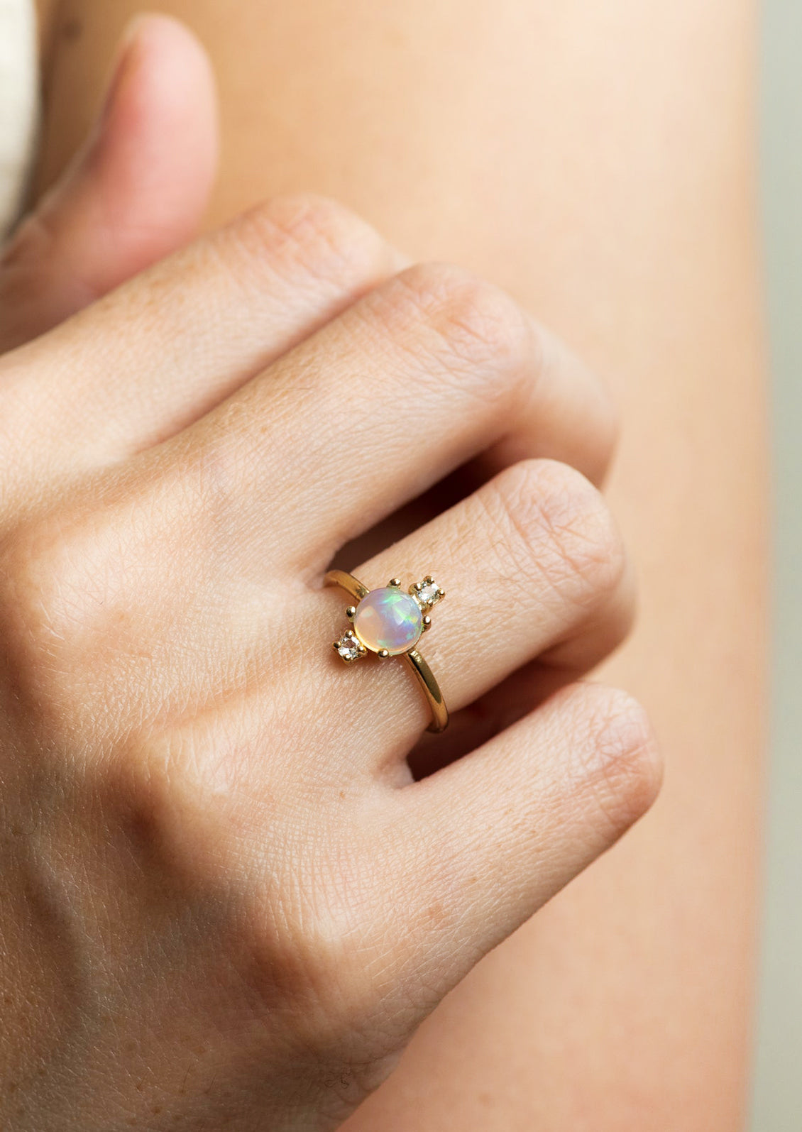 A gold ring with large center opal stone and two small white topaz stones.