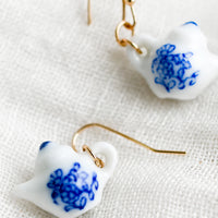 2: A pair of earrings in shape of white teapot with blue floral print.