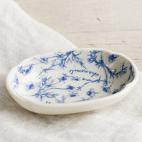 1: A small oval shaped dish in white with blue floral pattern.