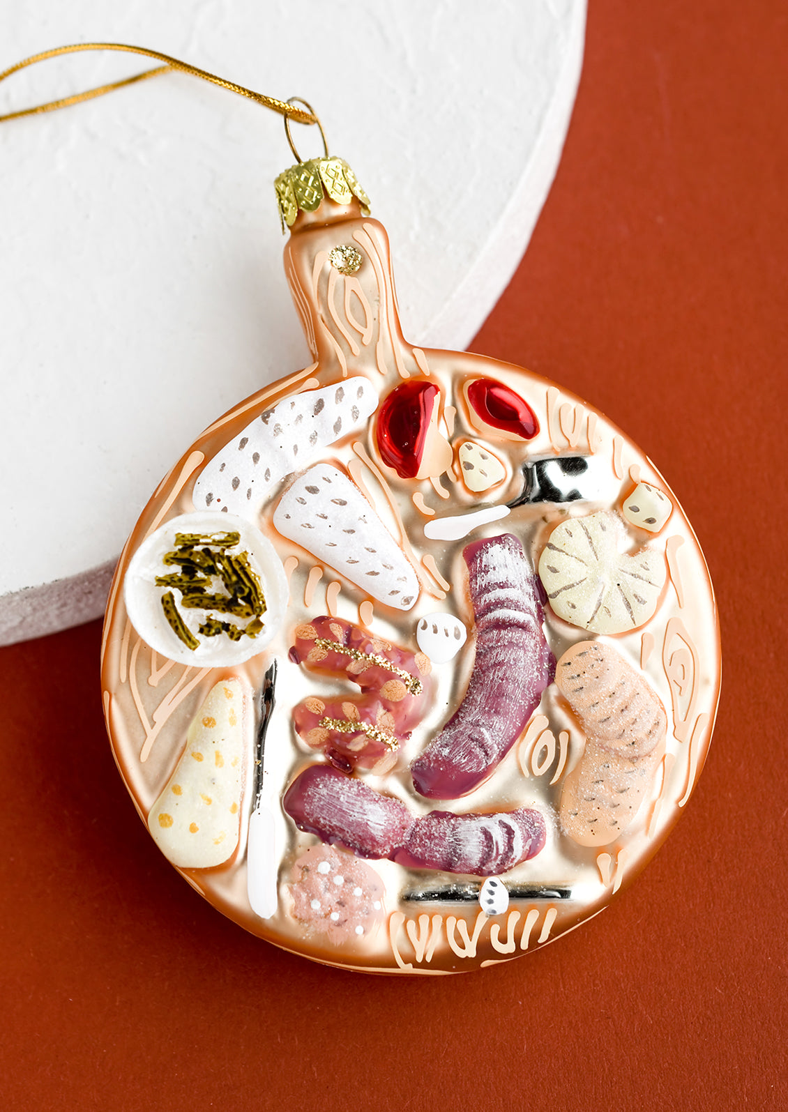 A glass ornament in the shape of a charcuterie board of meats and cheeses.