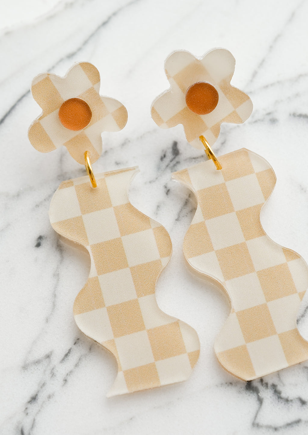 Beige Multi: A pair of beige checker print earrings in wavy flower shape.