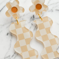 Beige Multi: A pair of beige checker print earrings in wavy flower shape.