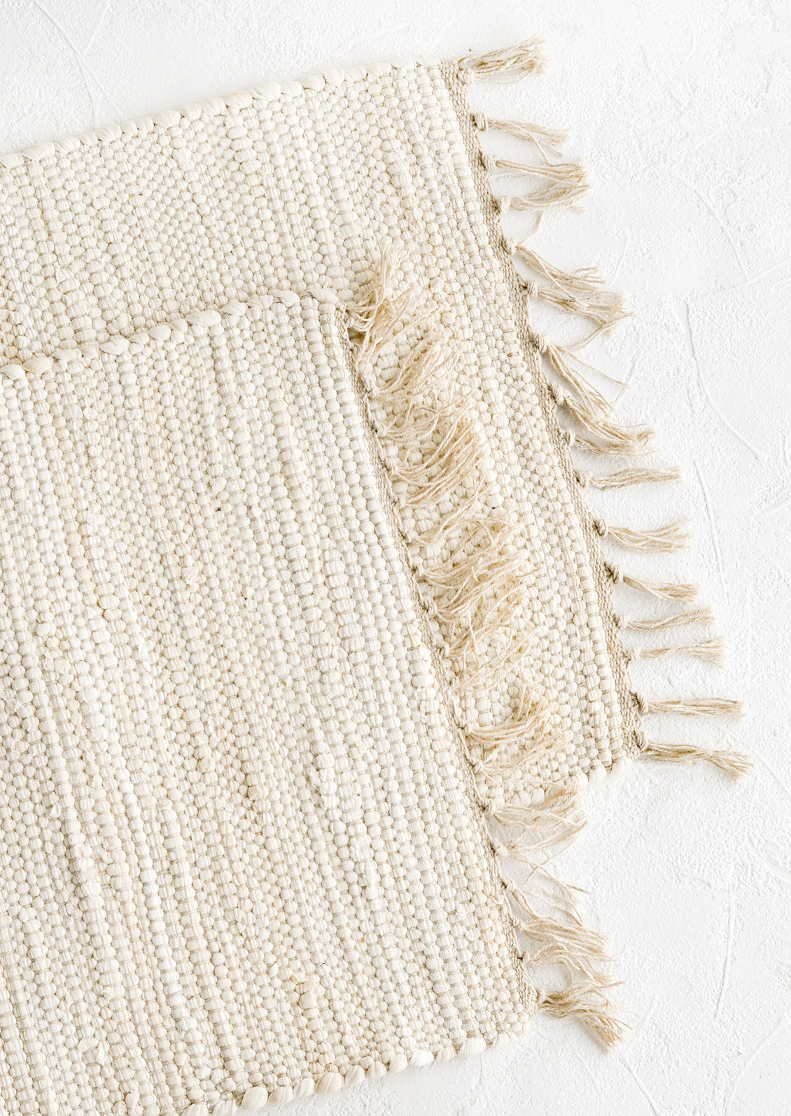 Two chindi weave placemats in ivory with tonal fringed trim.
