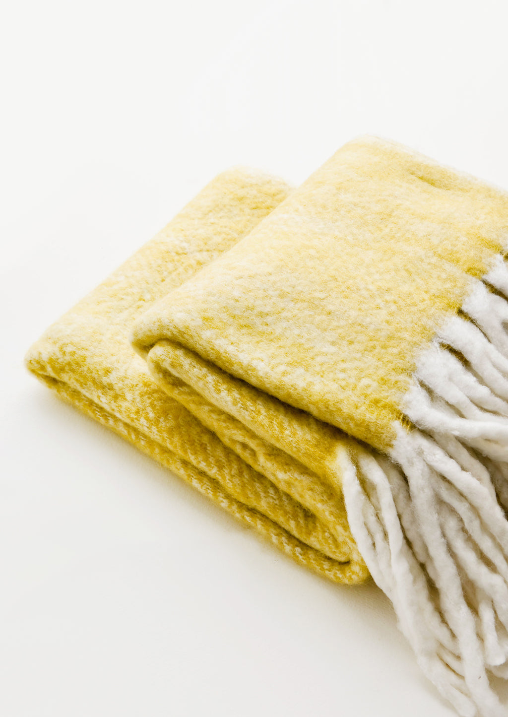 1: Plush and wooly yellow throw blanket with exaggerated fringe trim in ivory