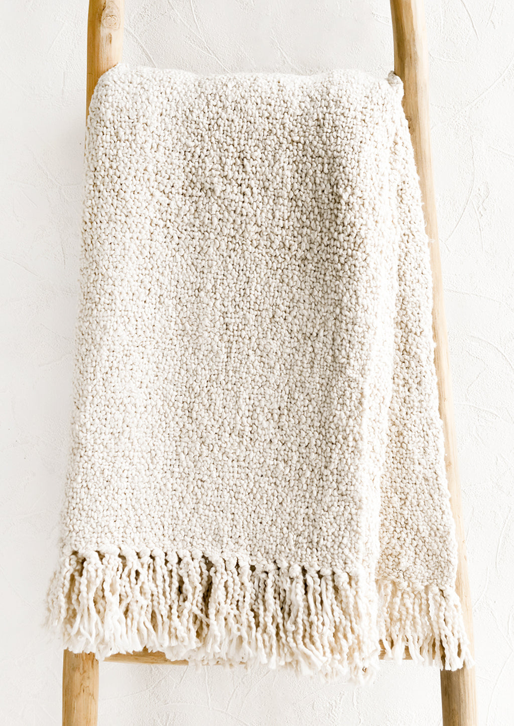 1: An ivory colored cotton throw with chunky boucle texture.