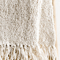 2: An ivory colored cotton throw with chunky boucle texture.