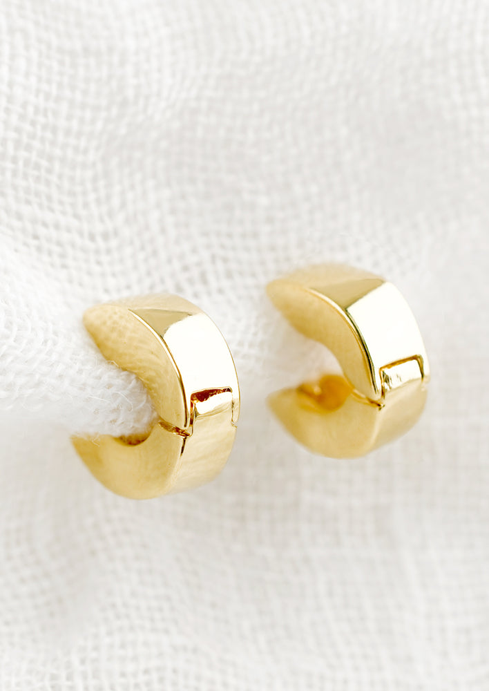 1: A pair of small gold huggie hoop earrings in chunky shape.