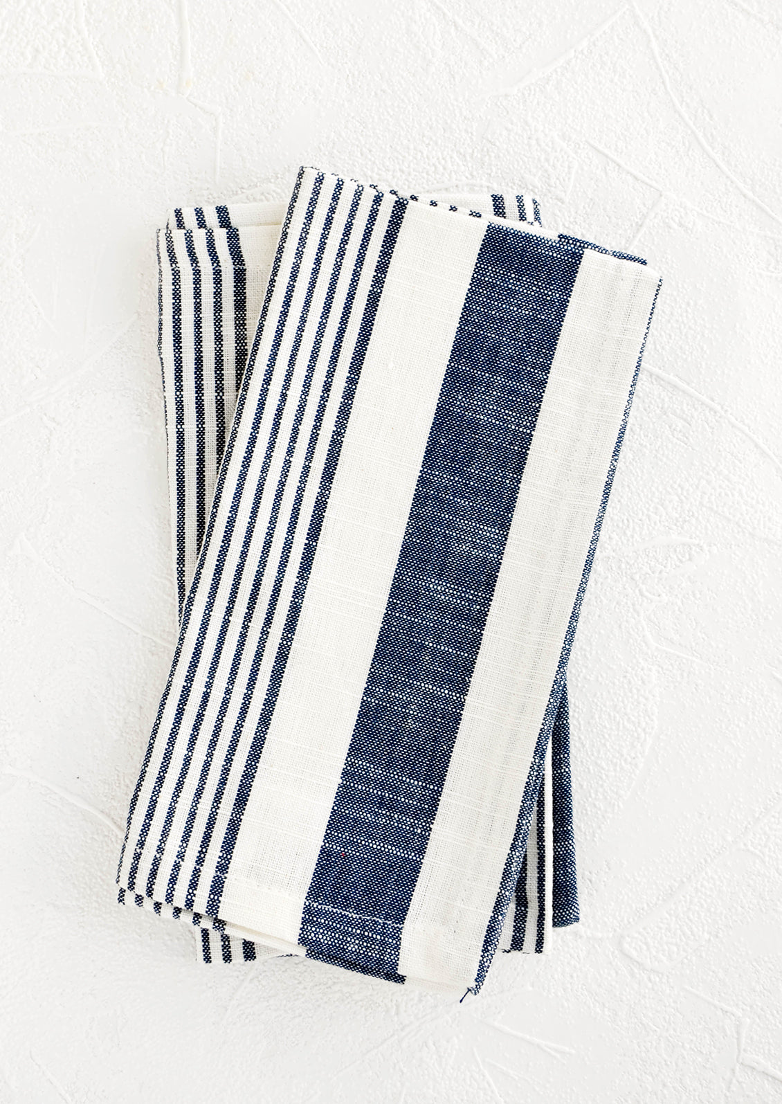 White and blue striped cotton napkins, pictured folded as a pair.