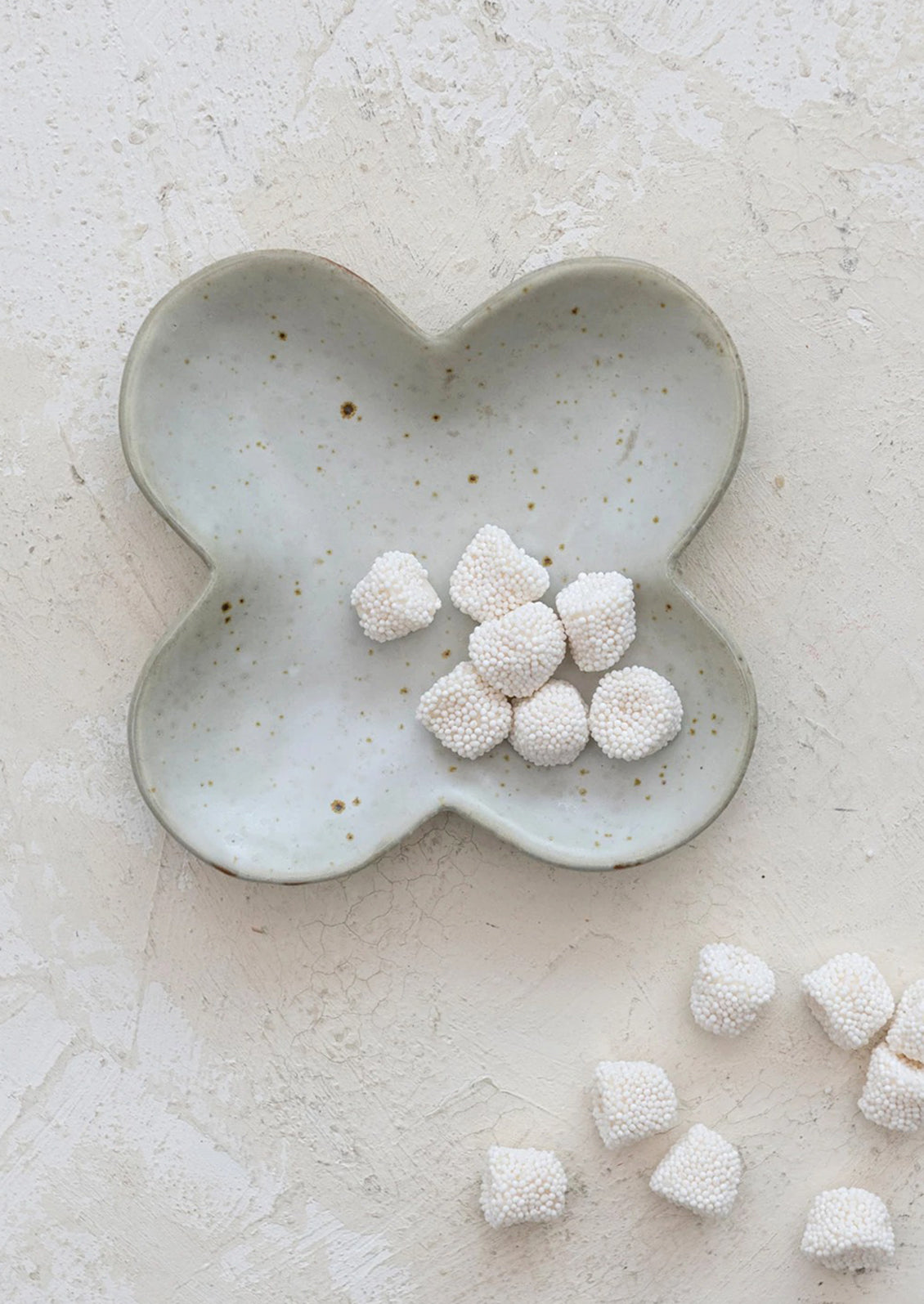 A clover shaped little dish in speckled white ceramic.